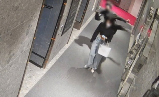 지난해 5월 22일 부산 부산진구 한 오피스텔 1층 복도에서 이른바 '부산 돌려차기'의 가해 남성(뒤쪽)이 뒤쪽에서  피해자를 발로 가격하는 모습이 CCTV에 찍혔다. [피해자 측 변호사 제공]
